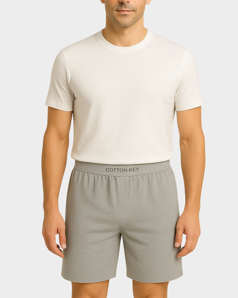 Front view of a male model wearing grey Cotton Key boxer shorts and a white t-shirt, showing the branded waistband against a white background