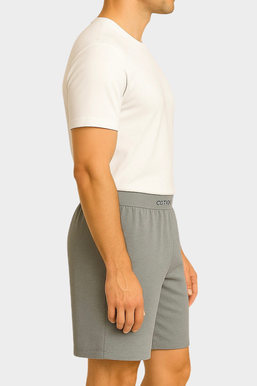 Side view of a male model wearing grey Cotton Key boxer shorts and a white t-shirt, standing against a light gray background